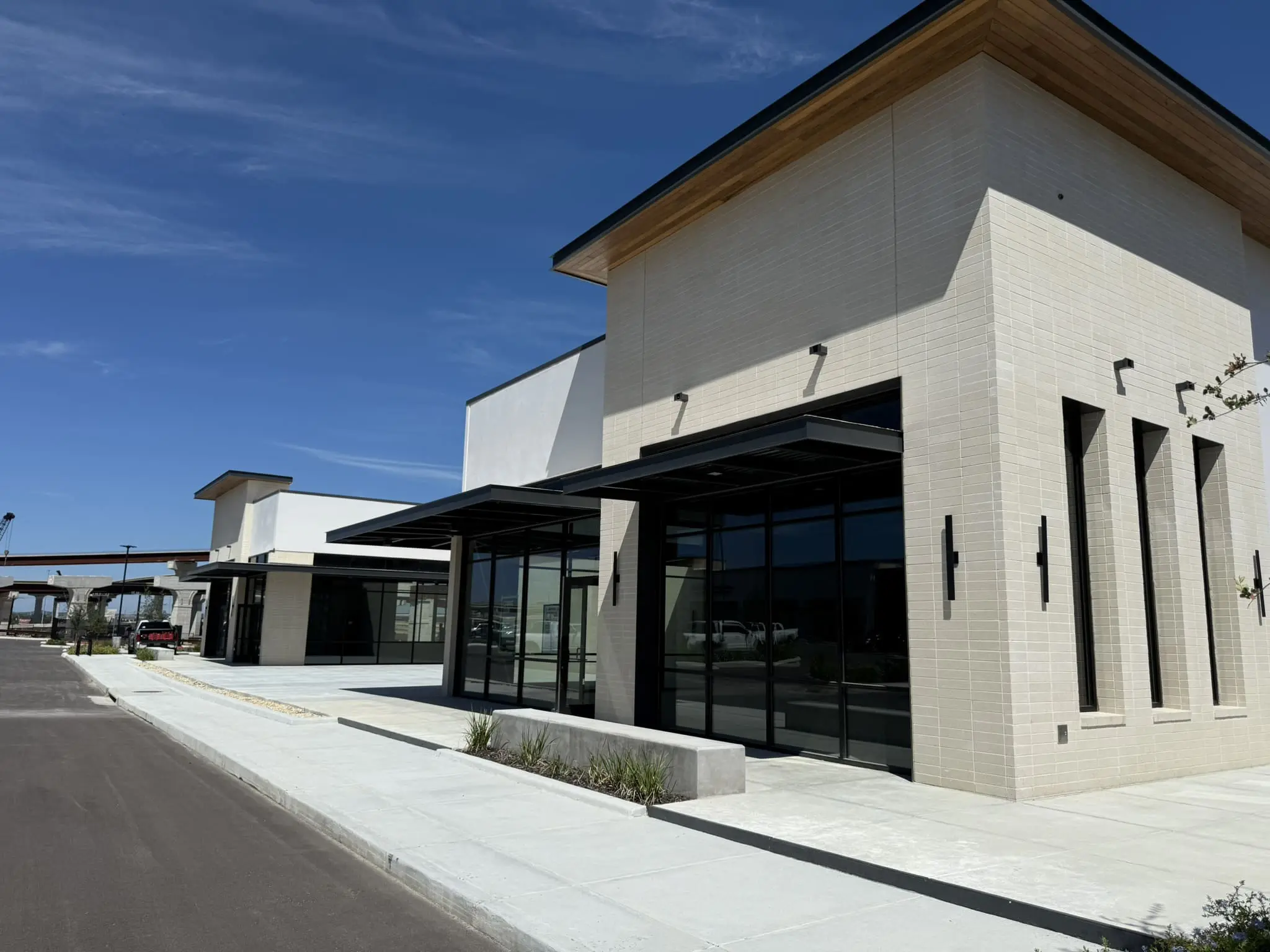 Exterior painting on a new retail center in Austin, TX with white painted stucco walls, light brick facades, black steel awnings, and storefront glass
